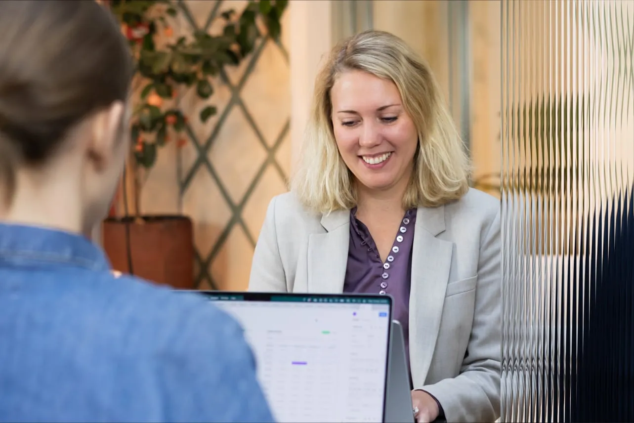 Two colleagues at a laptop in the Stockholm office, seen past a fluted glass wall